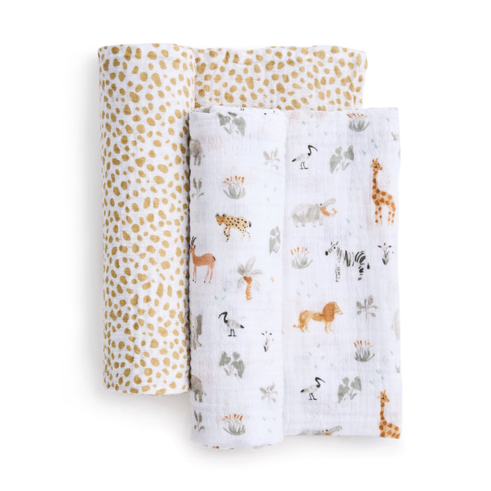Displayed are two essentials cotton muslin swaddle blankets from aden + anais. One features a white background with animal safari prints of lions, giraffes, and zebras; the other has a beige and white polka dot pattern. These breathable swaddles offer comfort for your little one.