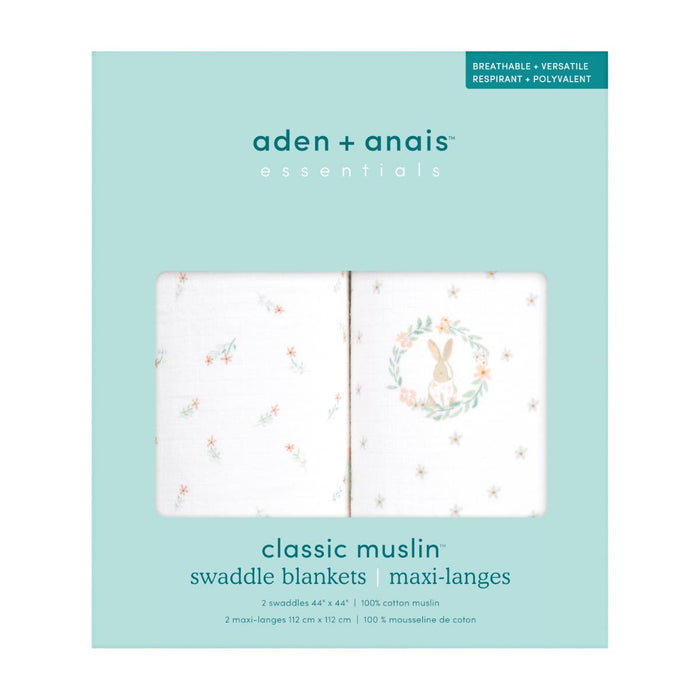 A light blue packaging box displays the aden + anais essentials cotton muslin swaddle blanket 2 pack. The clear window reveals two breathable cotton muslin blankets featuring delicate floral patterns and a charming rabbit illustration.