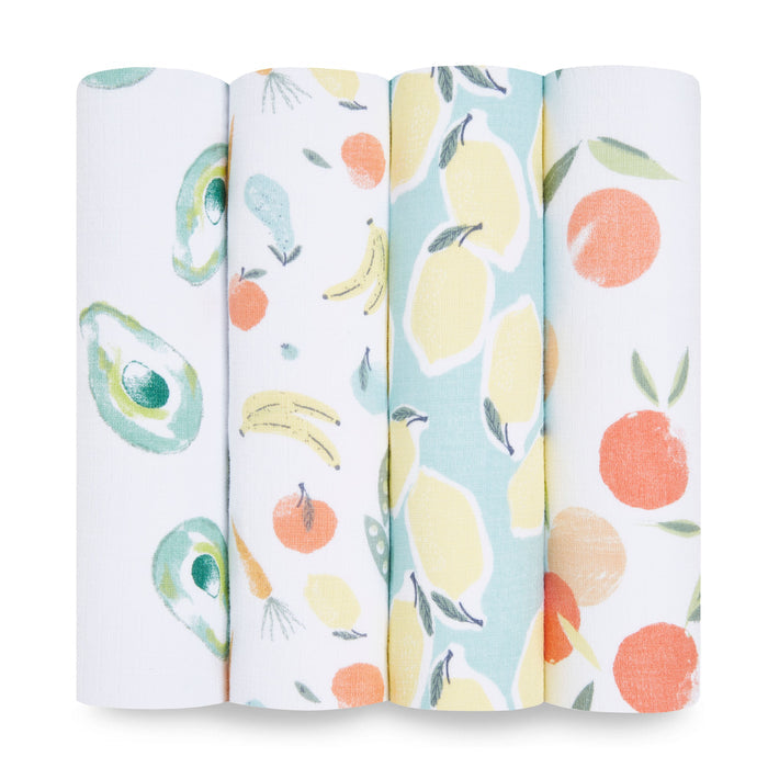 The aden + anais essentials cotton muslin swaddle blanket 4 pack includes four rolls of breathable white cotton muslin featuring vibrant fruit prints—avocados, bananas with oranges and pears, lemons, and oranges—all with slightly different background colors.