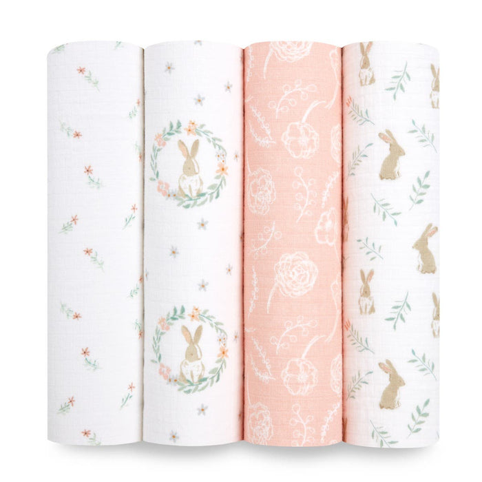 The aden + anais essentials cotton muslin swaddle blanket 4 pack includes soft, breathable fabric with whimsical designs like small flowers, rabbits in a wreath, hand-drawn roses on peach, and rabbits with leaves.