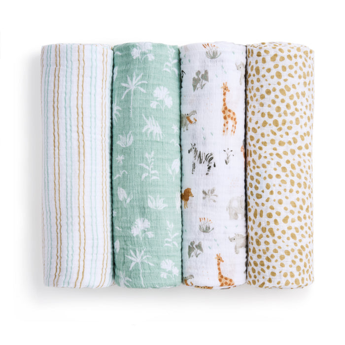 Four aden + anais cotton muslin swaddle blankets from the Essentials 4-pack are shown vertically: pastel stripes, green with white florals, white with safari animals, and white with mustard polka dots—all in soft muslin.