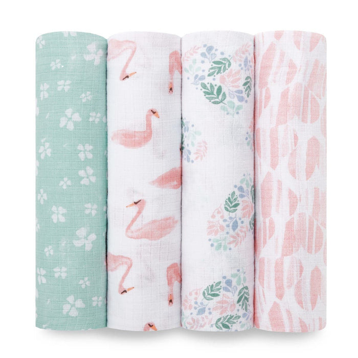 The aden + anais essentials cotton muslin swaddle blanket 4 pack features four vertically lined blankets: green with white flowers, white with pink flamingos, a pastel floral pattern on white, and white with pink abstract shapes, adding charm and practicality to any nursery.