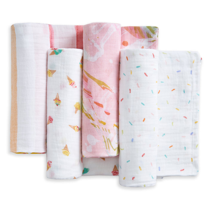 Four aden + anais essentials cotton muslin swaddle blankets, featuring orange stripes, ice cream cones, pink abstract, and rainbow confetti dot patterns, are arranged upright on a white background. Each is made from soft, breathable muslin.