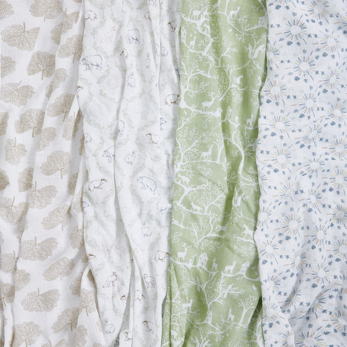 These essentials cotton muslin swaddles by aden + anais, feature breathable cotton and include four patterns: brown leaves, small brown animals on white, white nature scenes on green, and light blue with sunburst designs.