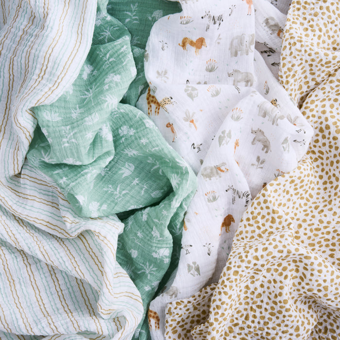 Explore aden + anais essentials cotton muslin swaddle blanket 4 pack, featuring soft prints: green with white dandelions, white with animals like horses and zebras, white with small brown spots, and pastel stripes.