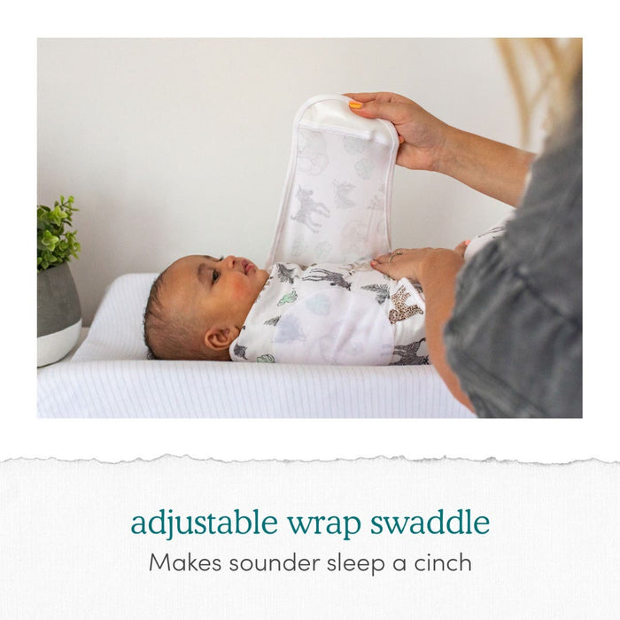 A baby rests serenely on a changing table wrapped in an essentials easy swaddle wrap by aden + anais, as adult hands secure it with adjustable fasteners for comfort and to prevent startle reflex. A plant adds ambiance to the scene. Text reads: essentials easy swaddle wrap 3 pack - Ensures a sounder sleep effortlessly.