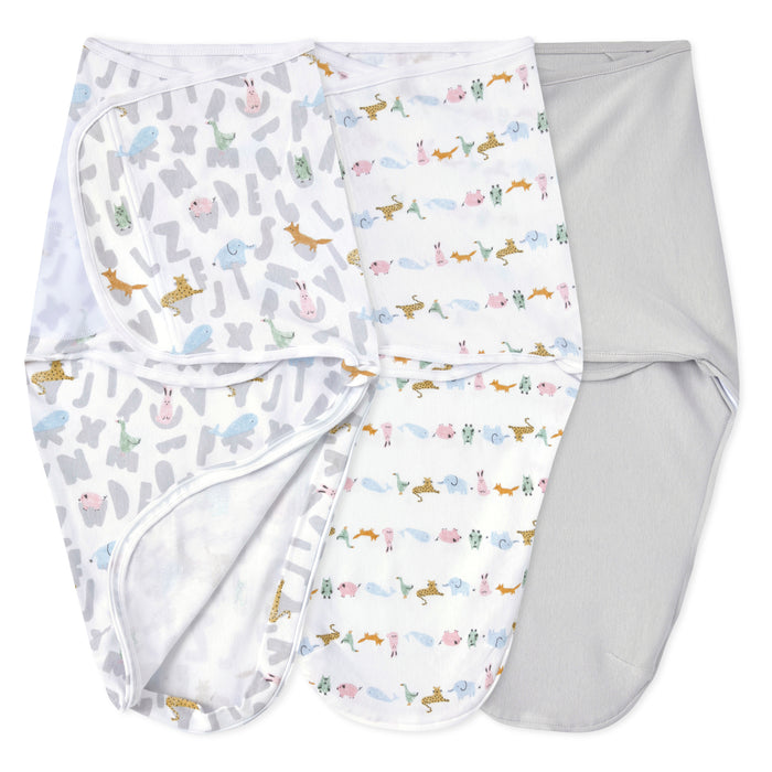 The aden + anais essentials easy swaddle wrap quick change 3 pack TOG 1.0 features two pastel animal and alphabet print wraps and one solid light gray, all laid out flat—ideal for cozy sleep or easy diaper changes.