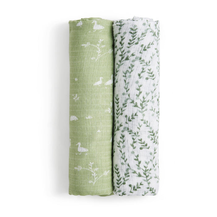 Two rolled viscose swaddles, part of the essentials silky soft swaddle blanket 2 pack by aden + anais, feature white ducks and plants on green beside a design of green leaves on white. These bamboo-infused fabrics are gentle for sensitive skin, ensuring comfort.