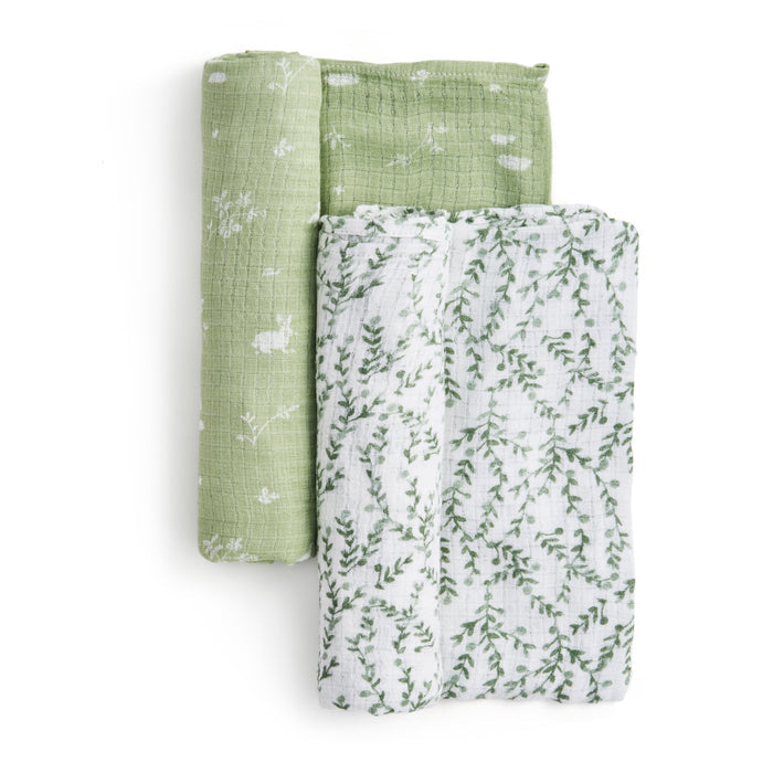 A stack of two essentials silky soft swaddle blankets by aden + anais features a top blanket in light green with a floral pattern and a bottom one in white with a green leafy design, all crafted from bamboo-infused viscose to ensure comfort and style for sensitive skin.