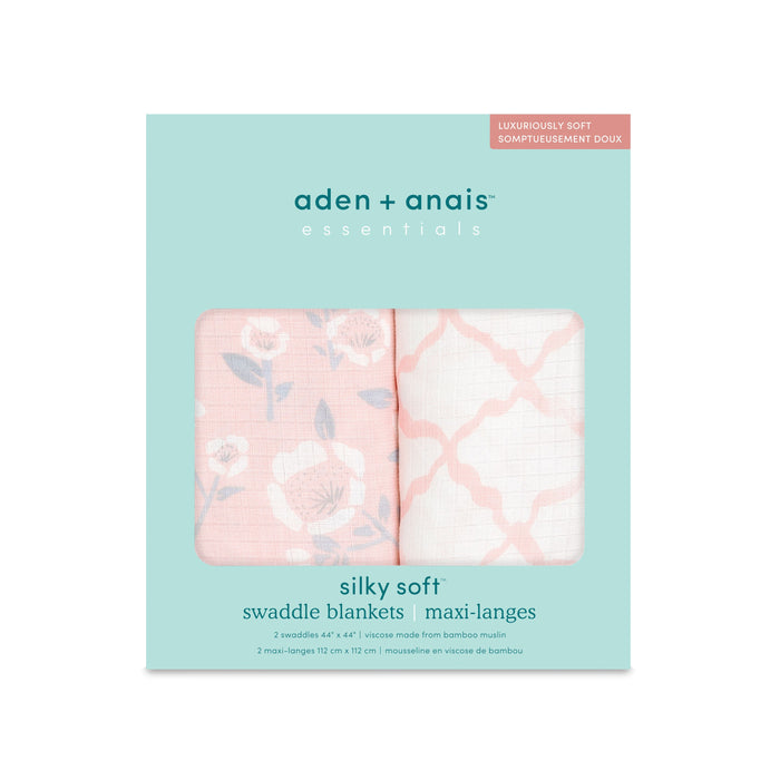 The aden + anais essentials silky soft swaddle blanket 2 pack features bamboo-infused viscose, ideal for sensitive skin. The packaging displays two swaddles: one with a floral print on peach and another with a peach geometric design on white.