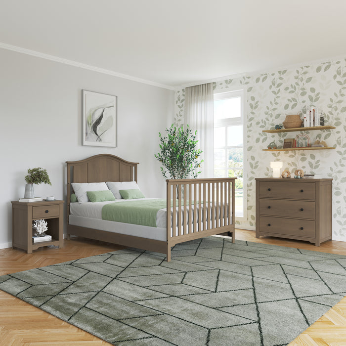 Bright bedroom with a Child Craft F06401 Full-Size Bed featuring Dusty Heather rails, green bedding, nightstand, dresser, leafy wallpaper, and a large rug. Natural light and greenery create a fresh, cozy vibe.