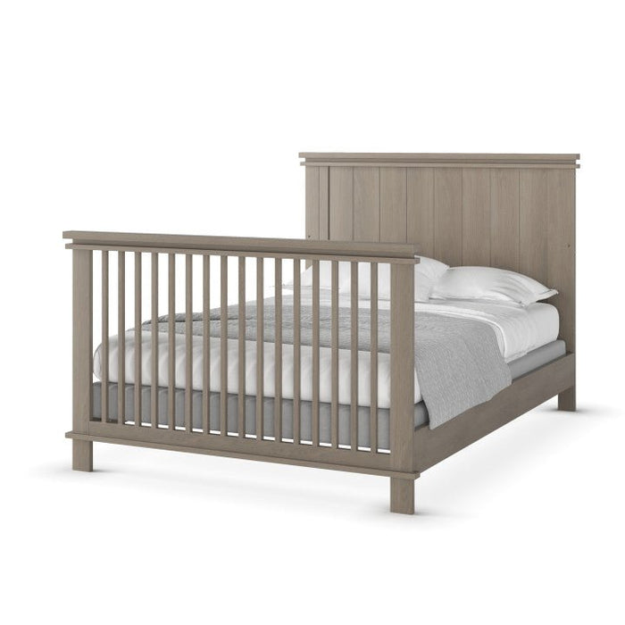 A minimalist full-size bed frame in Crescent Grey, featuring a slatted headboard and footboard, shown with white bedding and gray blanket. Compatible with Child Craft F06424 Full-Size Bed Rails for added versatility.