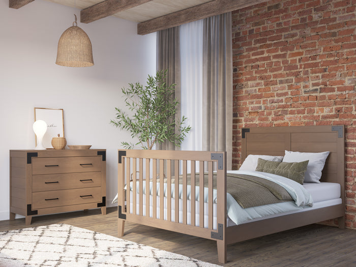 A cozy bedroom with a wooden crib that converts to a full-size bed using the Child Craft F06464 Full-Size Bed Rail in Dusty Heather, a matching dresser, exposed brick wall, potted plant by the window with long curtains, and a woven pendant light.