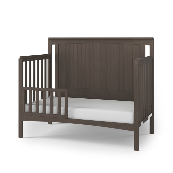 The Child Craft F09501 Toddler Guard Rail in Dapper Gray features strong wood construction with a high back panel, slatted sides, and an open front rail, shown with a white mattress on a white background.