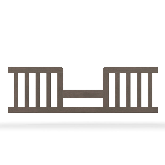 The Child Craft F09514 Toddler Guard Rail in Dapper Grey features vertical slats, an open center with a horizontal support bar, and is designed for easy crib-to-toddler bed conversion while providing added safety for your child.