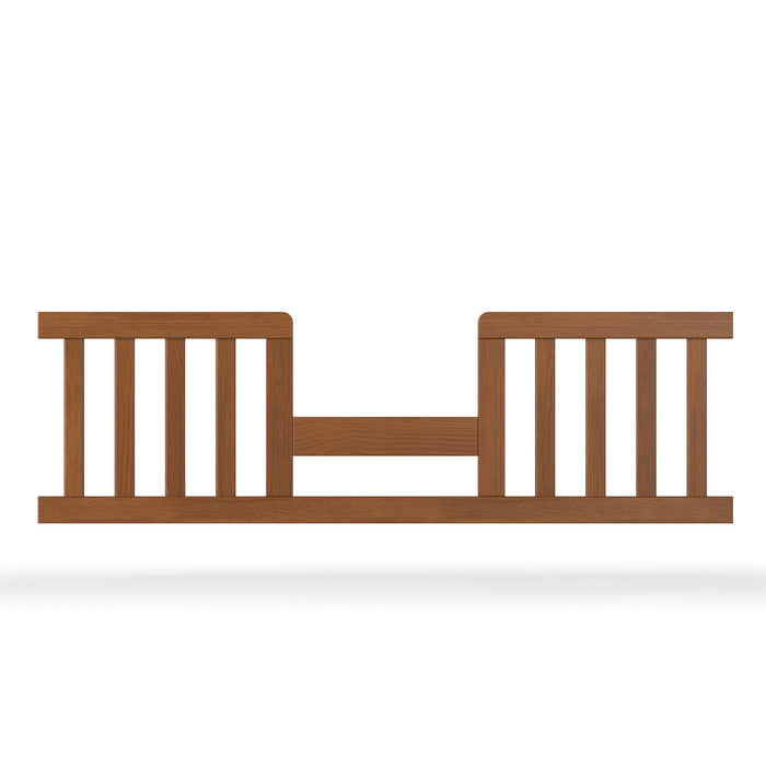 The Child Craft F09514 Toddler Guard Rail in Coach Cherry features vertical slats and an open center, attaching to the side of a crib toddler bed to enhance safety and security.
