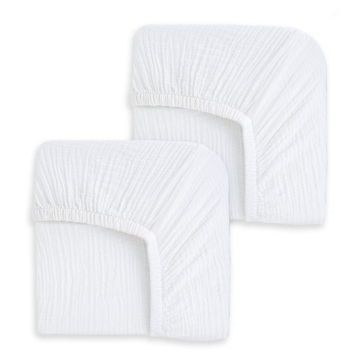 Two HALO Fitted Crib Sheets, 100% organic cotton muslin in white, come as a 2-pack with elastic corners and a soft, breathable feel, displayed side by side on a white background.