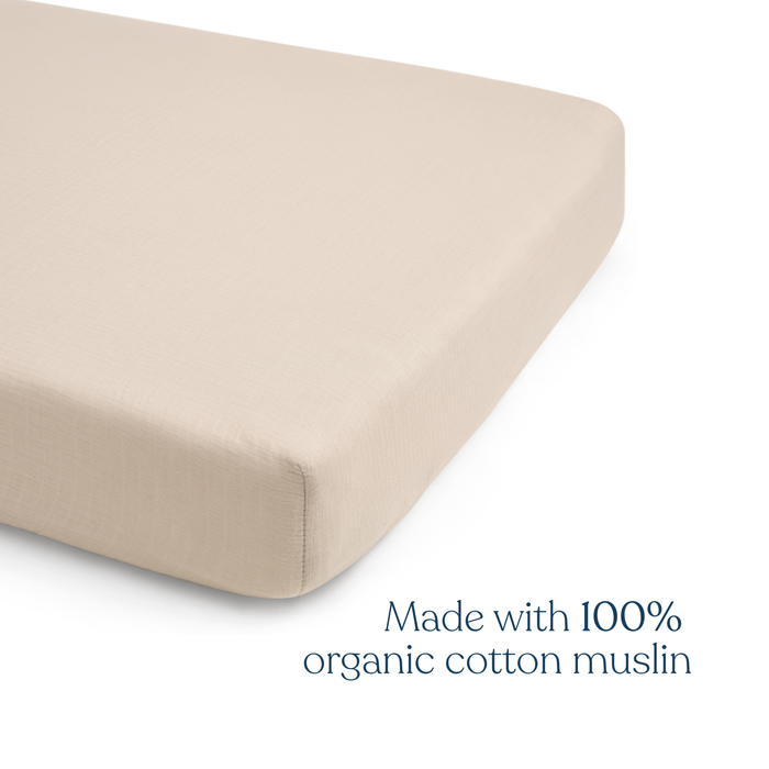 The HALO Fitted Crib Sheets 100% Organic Cotton Muslin 2 Pack features beige sheets on a mattress with “Made with 100% organic cotton muslin” text—ideal for parents wanting soft, breathable crib sheets for their nursery.