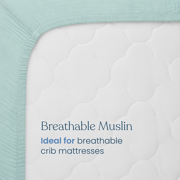 A close-up of a HALO Fitted Crib Sheet 100% Organic Cotton Muslin, shown in light blue with a quilted, cloud-like pattern. Text on the mattress reads: Breathable Muslin. Comes in a convenient 2 pack—ideal for breathable crib mattresses.