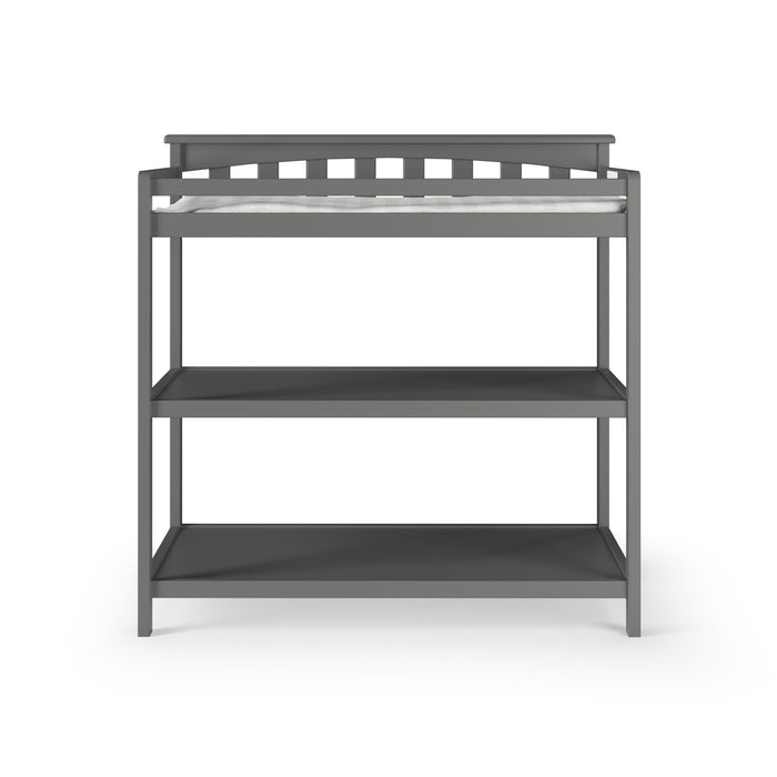 The Child Craft Flat Top Baby Changing Table in Cool Gray features baby-safe finishes, a slatted back, two open nursery storage shelves, and a white changing pad, all set against a white background.
