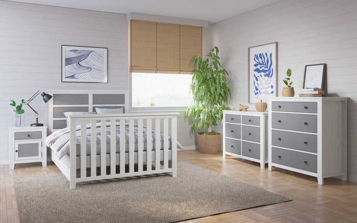 A bright, modern bedroom features white and gray furniture, including the Child Craft Full-Size Bed Rails in White/Gray, nightstand, dresser, a large potted plant, abstract wall art, and a window with bamboo blinds letting in natural light.