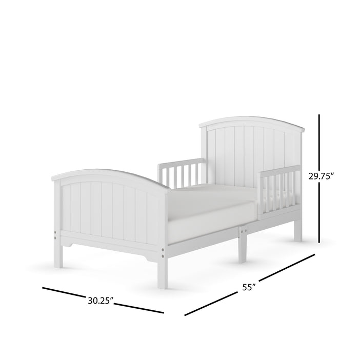 The Child Craft Hampton Toddler Bed in matte white features guard rails, a slatted headboard and footboard, partial side rails, and a low profile for easy access. Dimensions: 30.25"W x 55"L x 29.75"H. Shown on a white background.