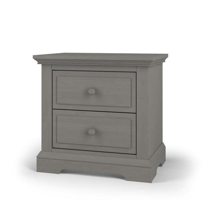 The Child Craft Jordyn Nightstand in Lunar Gray features baby-safe finishes, two drawers with round knobs, and a classic design with crown molding and a subtly curved base. Ready to assemble.