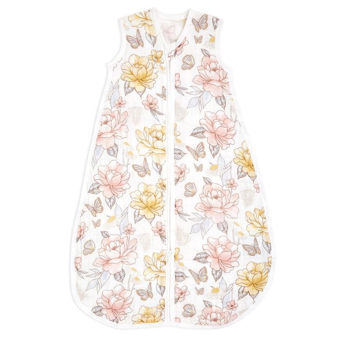The aden + anais organic cotton light sleep sack TOG 1.0 is a sleeveless baby sleep sack made from 100% organic cotton muslin. It features a zipper and adorns a charming floral pattern with pink, yellow, and beige flowers plus tiny butterflies on white, perfect for those seeking organic options.