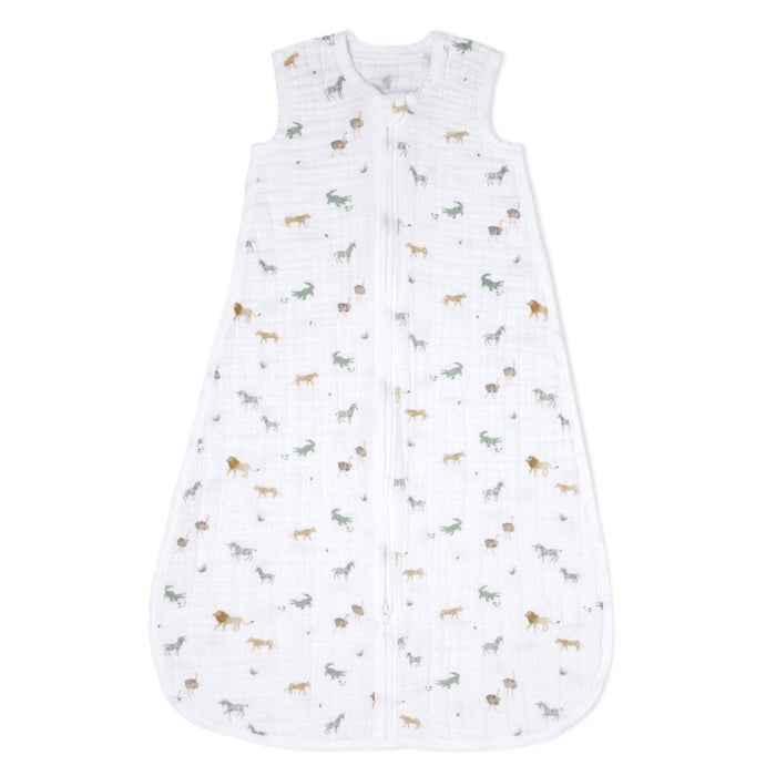 The aden + anais organic cotton light sleep sack TOG 1.0 is a sleeveless, GOTS-certified white muslin sleep sack with a front zipper, decorated with small, colorful animal prints of lions, zebras, and giraffes.