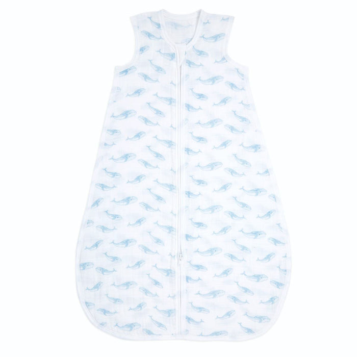 The aden + anais organic cotton light sleep sack TOG 1.0, in white muslin and adorned with light blue whale illustrations, boasts a sleeveless design and a front zipper. It ensures your babys comfort and style while being GOTS certified.
