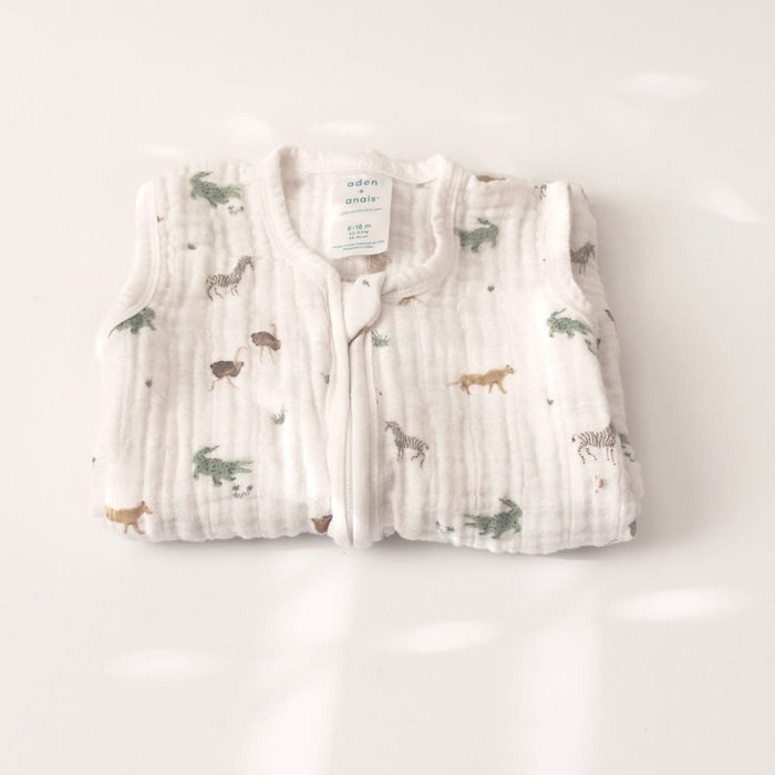 This light sleep sack, crafted from 100% organic cotton muslin by aden + anais, showcases a delightful nature-themed pattern featuring zebras and lions. The soft fabric includes a visible label displaying the size and brand elegantly set against its light surface. TOG rating is 1.0.