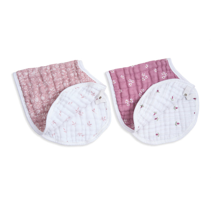 Two aden + anais organic cotton muslin burpy bib sets, each comprising a pink cloth with white flowers and a white cloth with pink flowers. The curved design includes white trim and snap closures for stylish functionality. GOTS-certified floral patterns add charm.