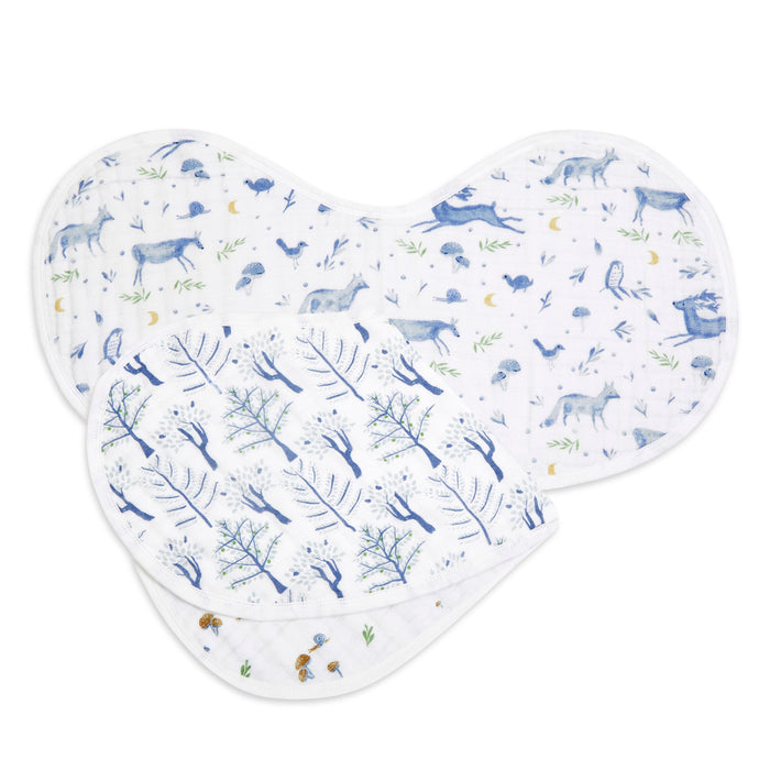 The aden + anais organic cotton muslin burpy bibs 2 pack features GOTS certified, soft fabric with whimsical woodland animals and plants on one bib, and leafless trees with birds on the other, both in blue and white prints.