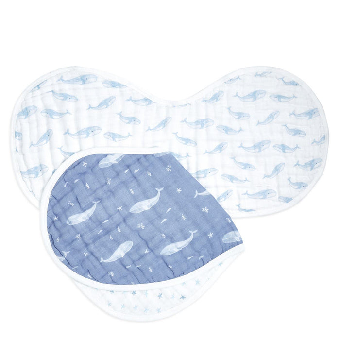 The aden + anais organic cotton muslin burpy bibs 2 pack features two bibs with charming whale designs: one blue with white whales and the other white with light blue whales, complemented by a blue and white star design. Theyre stylefully arranged in an overlapping fan-like display.