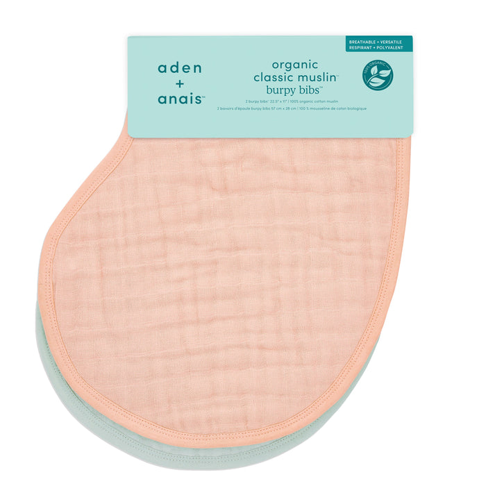 The aden + anais organic cotton muslin burpy bibs 2 pack includes two GOTS certified bibs, one in peach and one in mint green. These soft, absorbent, and versatile baby burp cloths are ideal for burping and feeding, with a packaging label at the top.