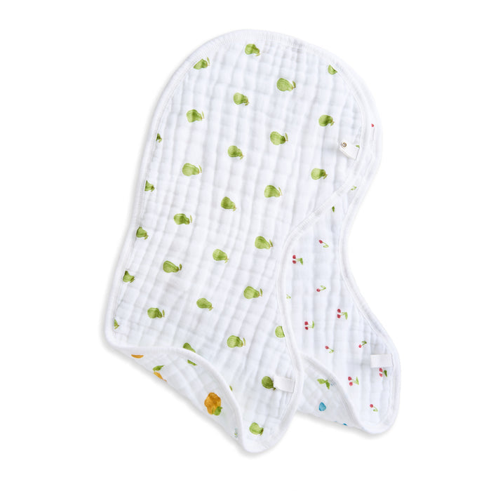 The aden + anais organic cotton muslin burpy bibs 2 pack features two white GOTS certified bibs with quilted texture and colorful prints: one with green leaf patterns, the other with cherry-like symbols, stylishly layered on each other.