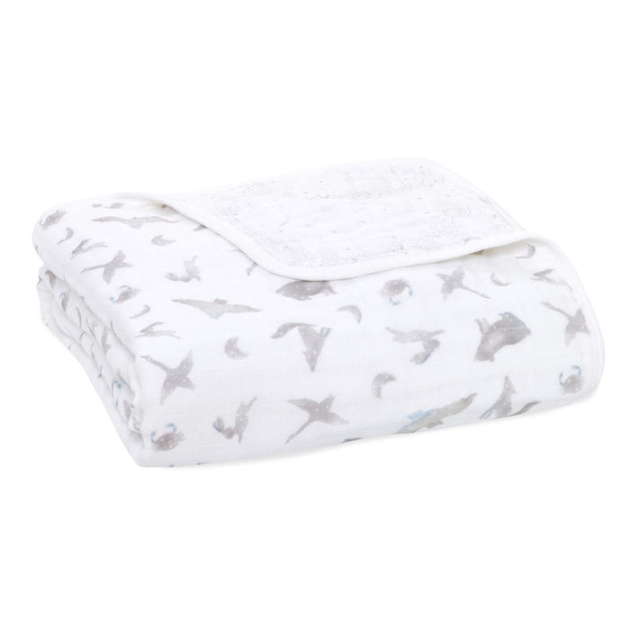 The folded aden + anais organic cotton dream blanket in white features subtle gray moons and whales, offering a gentle touch ideal for a baby blanket.