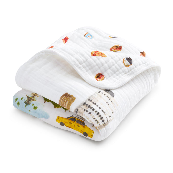 The aden + anais organic cotton muslin dream blanket is a soft white baby blanket with colorful city-themed prints—pizza, bagels, the Capitol dome, and a yellow taxi—perfect for little explorers.