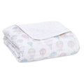 The aden + anais organic cotton dream blanket is a folded white muslin featuring pastel hot air balloon illustrations. GOTS certified, it’s soft, lightweight, and ideal for babies or as charming decor.
