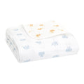 A folded aden + anais organic cotton dream blanket, GOTS certified, showcases charming blue elephant prints on soft muslin. The second corner playfully features delightful orange lion prints.