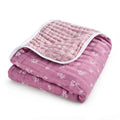 The aden + anais organic cotton muslin dream blanket, GOTS certified, is neatly folded to show its pink floral pattern with a white border and detailed inner floral design.