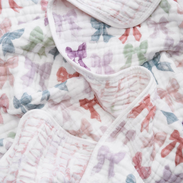 The aden + anais organic cotton muslin dream blanket features a soft, crumpled white fabric with pastel bows in pink, purple, blue, and green—perfect for adding a gentle touch to your baby's crib bedding.