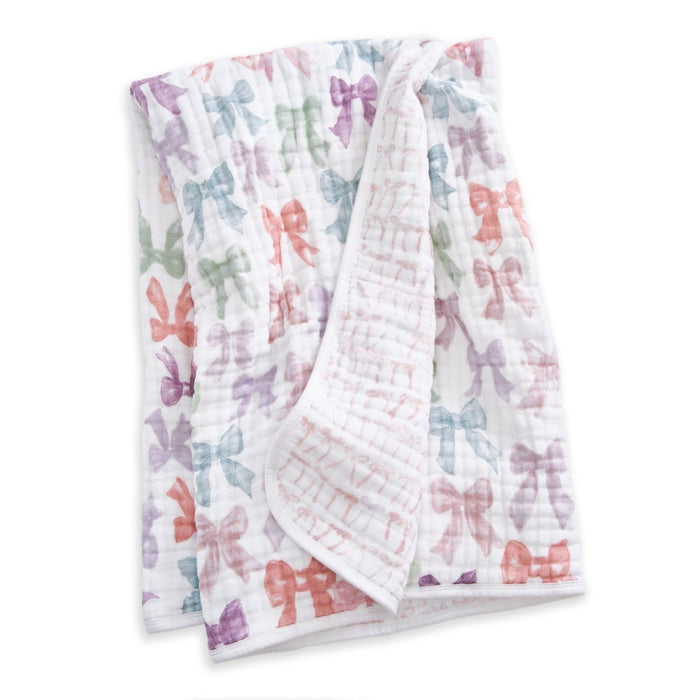 The aden + anais organic cotton muslin dream blanket features a soft, white quilted design with pastel bows in pink, purple, green, and orange—ideal for cozy crib bedding.