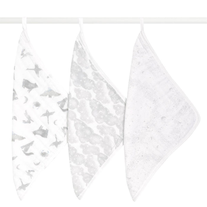 Three aden + anais organic cotton muslin oversized washcloths in white hang on a rod: the first with gray animal and star patterns, the second with gray circles, and the third with subtle starry dots. These stylish, eco-friendly washcloths ensure your little ones comfort.