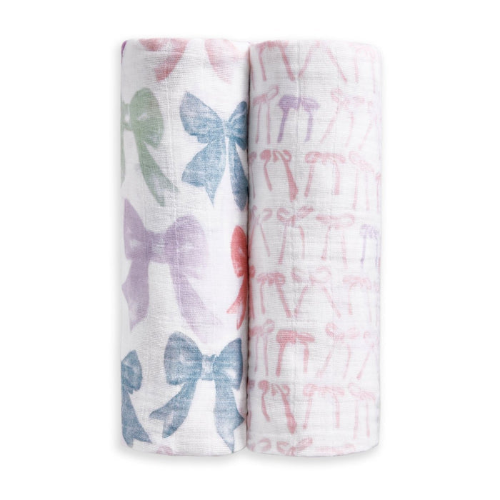 The aden + anais organic cotton muslin swaddle blanket 2 pack includes two blankets: one featuring large pastel bows and the other with a pattern of small pink bows.