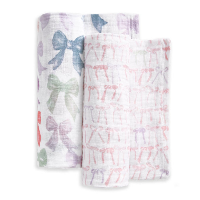 The aden + anais organic cotton muslin swaddle blanket 2 pack features two blankets—one with large, colorful bows and one with small pink bows—rolled side by side on a white background.