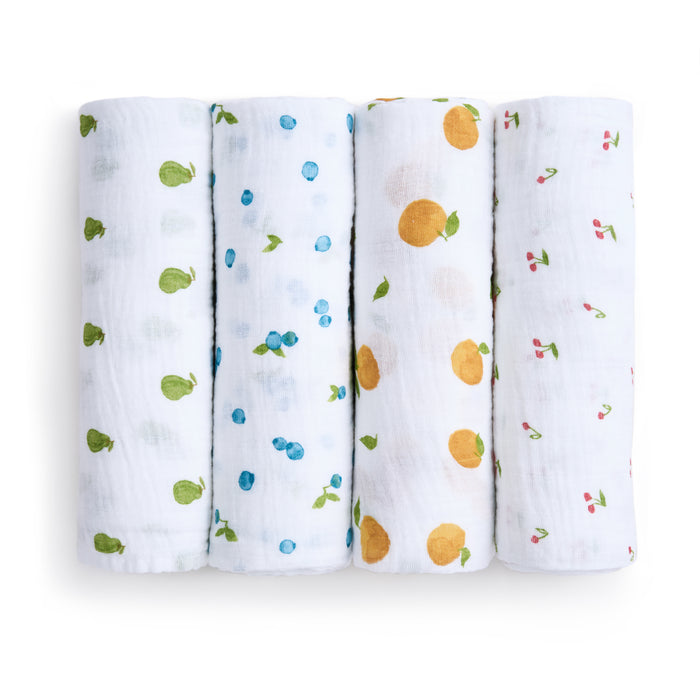 The aden + anais organic cotton muslin swaddle blanket 4 pack features four vertically arranged blankets, each adorned with different fruit patterns: green pears, blue berries, orange oranges, and red cherries—add a playful, sustainable touch to your baby product collection with these GOTS certified cloths.
