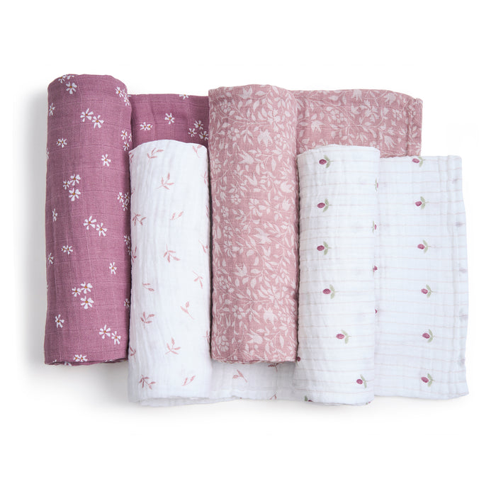 Four rolled-up organic cotton muslin swaddle blankets from aden + anais in pastel pink and white with floral patterns, including small blossoms and leaf motifs. These GOTS-certified fabrics are perfect for sustainable blanket creations.