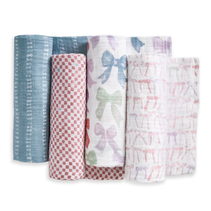 The aden + anais organic cotton muslin swaddle blanket 4 pack includes blankets with patterns: blue with white bows, red and white checkerboard, multicolored bows on white, and pink bows on white.