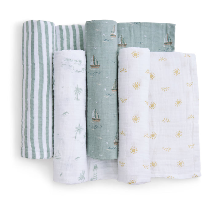 Five organically crafted aden + anais muslin swaddles are showcased, displaying patterns like green/white stripes, sailboats on green or white, palm trees on white, and yellow suns on white. They boast a soft and lightweight texture.